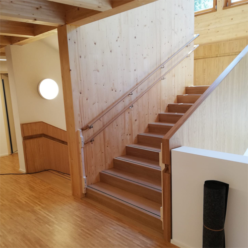 Holztreppe mit Treppenlauf und Antirutschschiene auf den Stufen