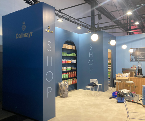 Messestand Shop mit Empfangstheke Streifen, beleuchtetem Shopregal, Hockern, Tischen, Regalen